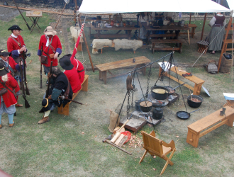 Re enactors in English uniform close to cooking fires