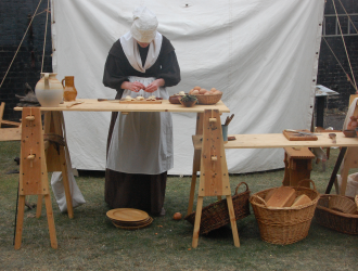 17th Century woman preparing food on trestle table