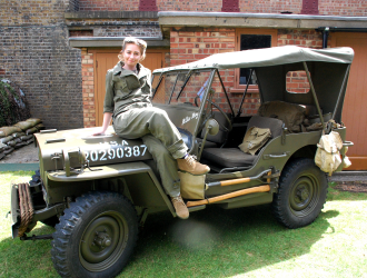 Young woman in US Army uniform posing on bonnet of Jeep